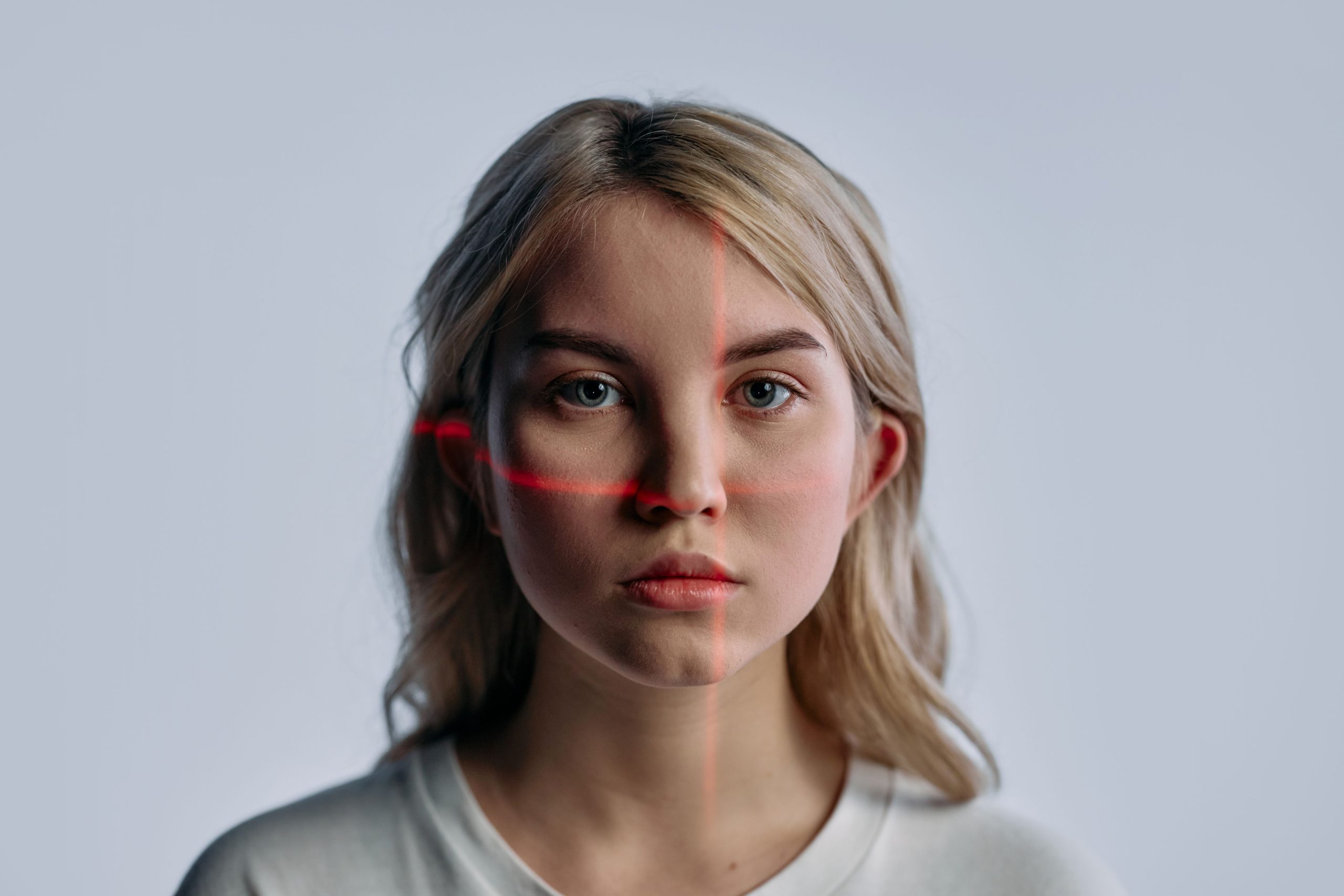 Woman's face scanned with facial recognition laser lines, illustrating deepfake and AI-generated imagery technology