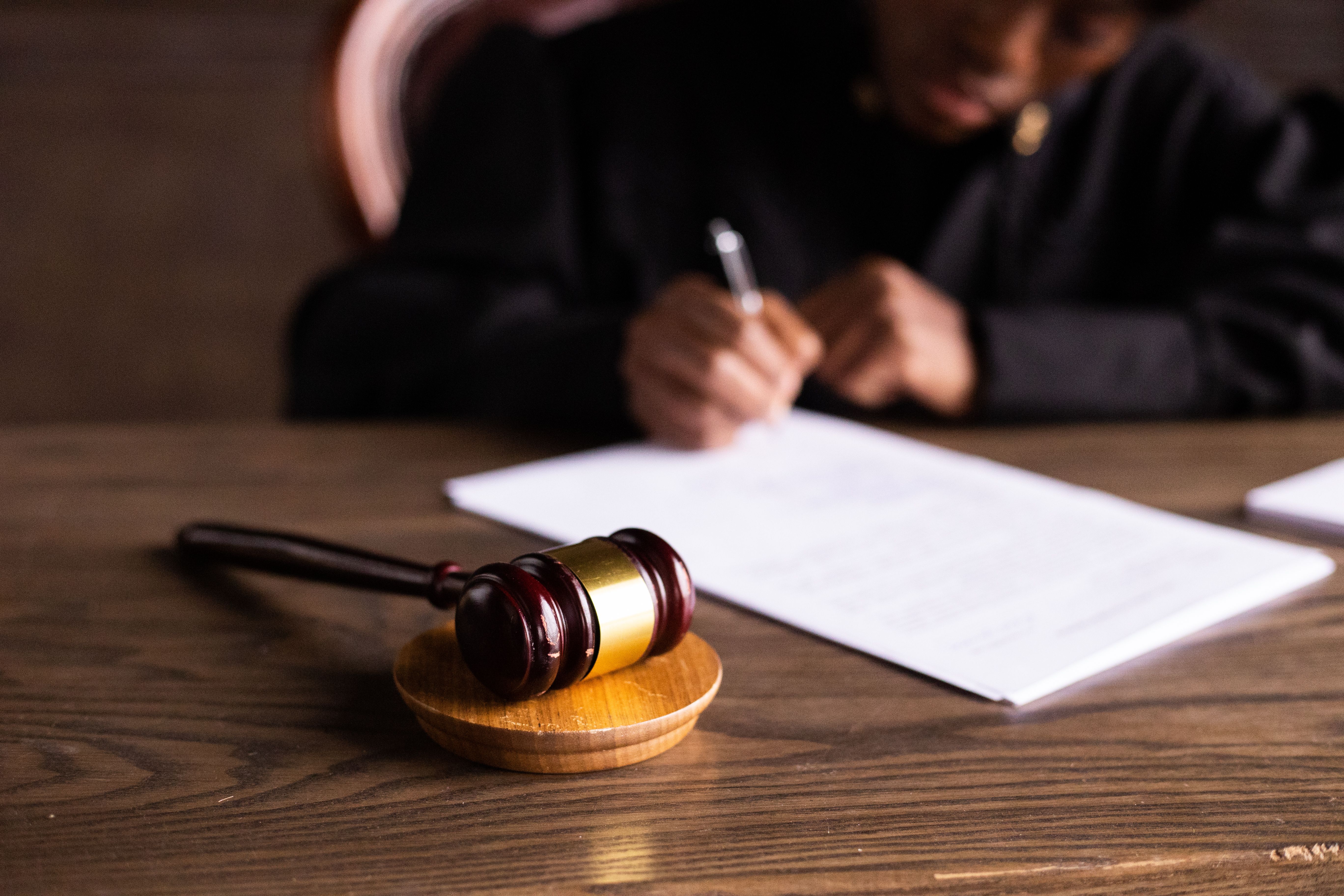 Judge signing legal documents at a desk with a gavel, representing courtroom authentication of evidence